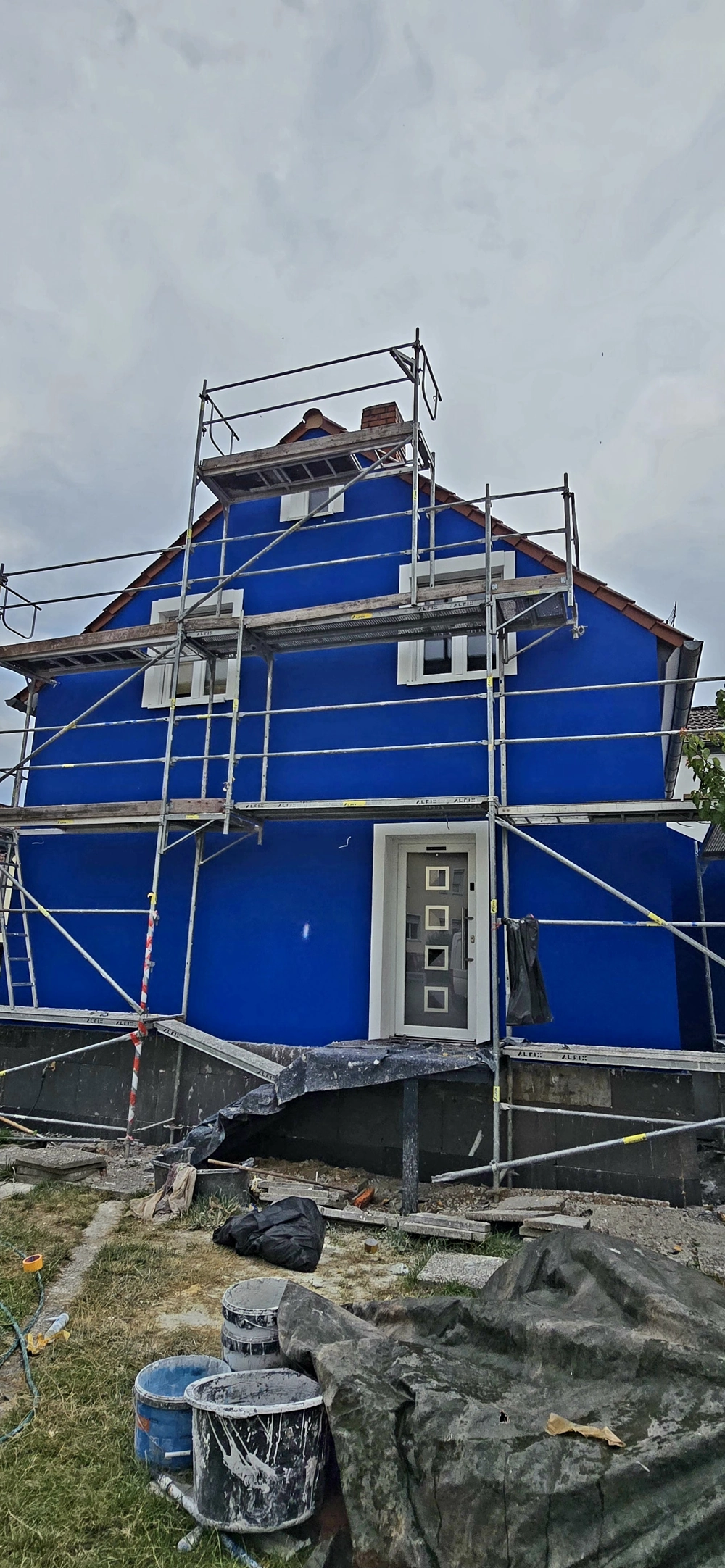 Hausfront mit Gerüst und blauer Außendämmung (WDVS)