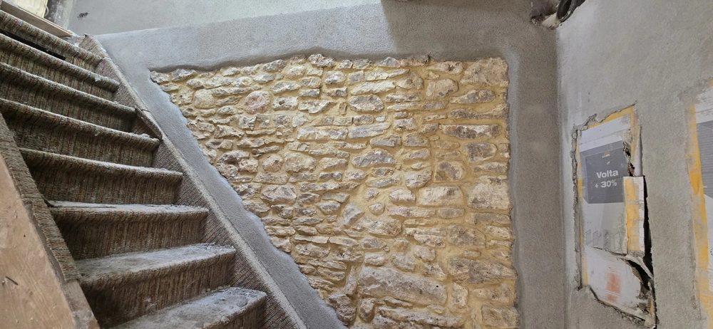 Treppenhaus mit freigelegter Natursteinwand und frisch verputzten Flächen für Naturstein Wandverkleidung