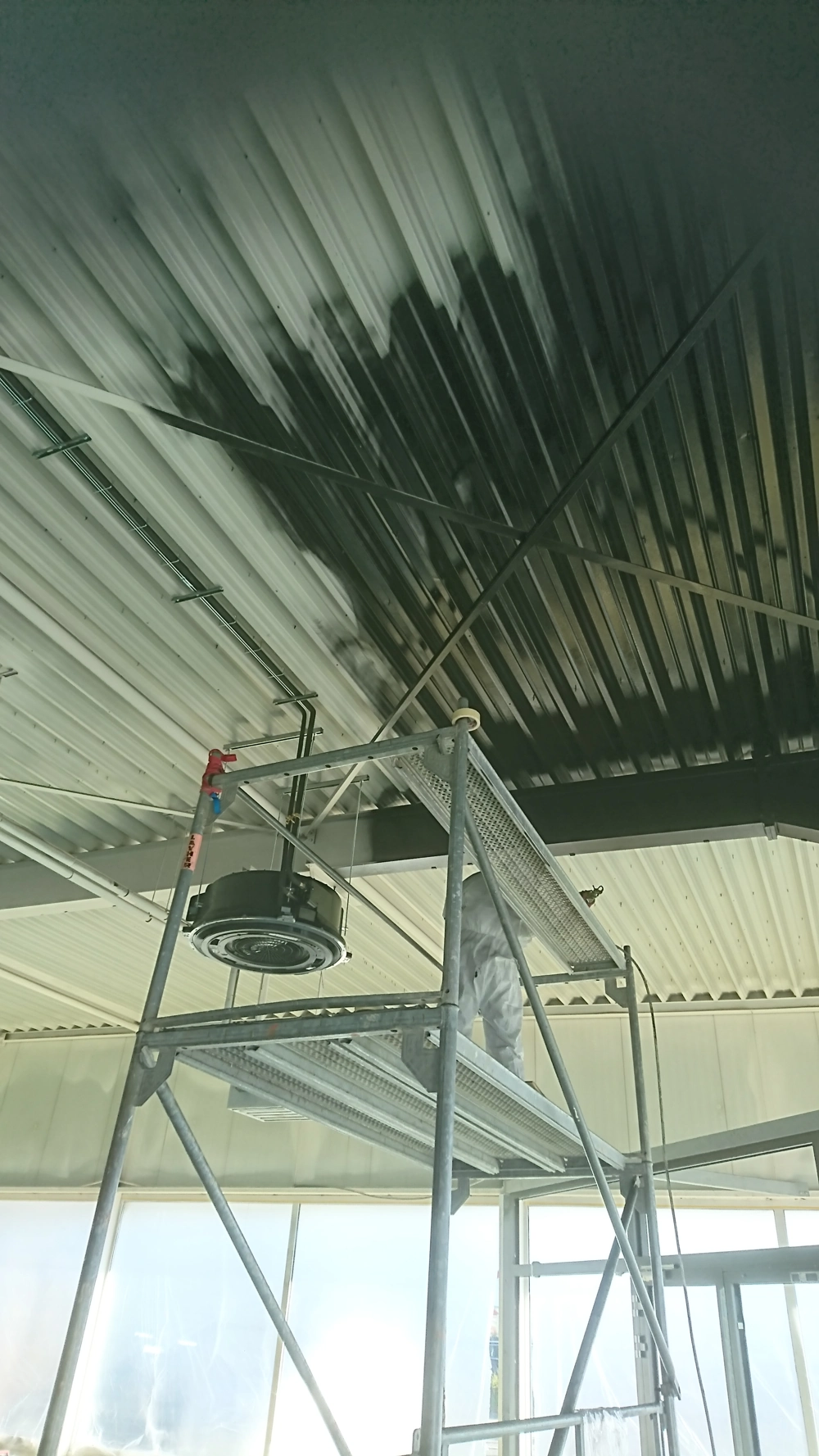 Mitarbeiter auf Gerüst bei Spachtelarbeiten an abgehängter Decke im Innenraum