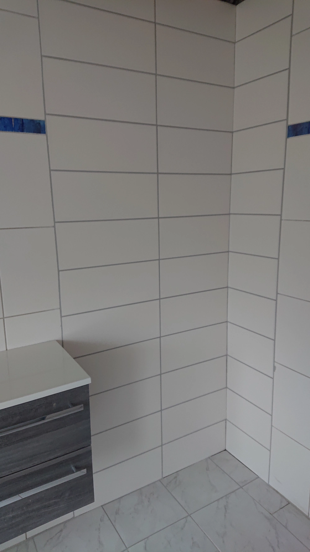 Ecke mit neu verlegten weißen Wand- und Bodenfliesen für Fliesen verlegen