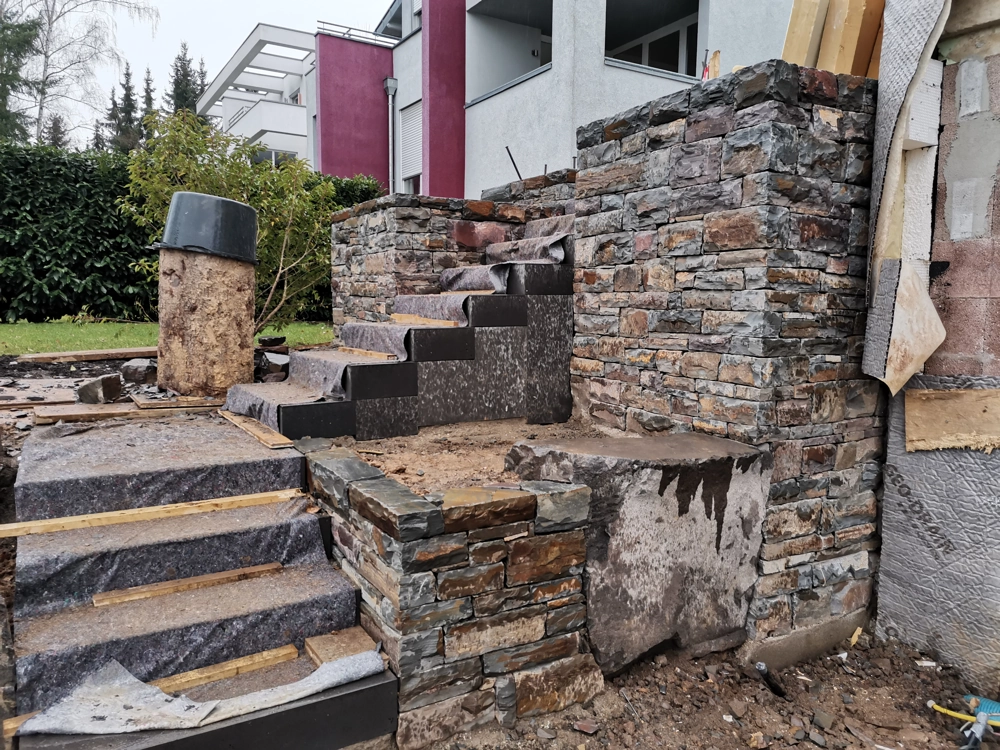 Rohbau-Treppe mit Naturstein-Wandverkleidung und Pflasterarbeiten im Außenbereich