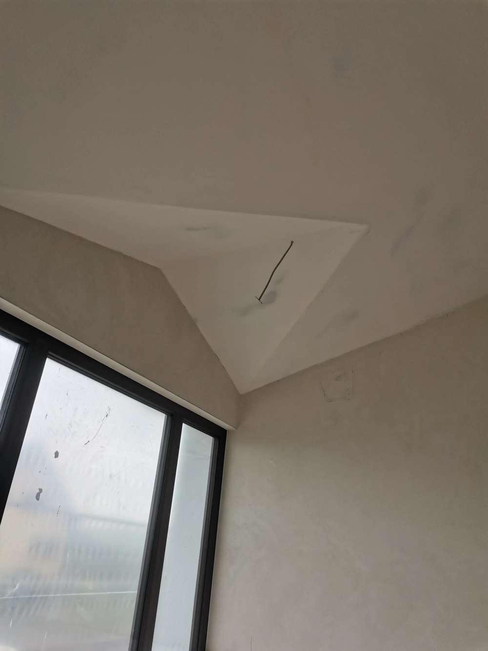 Abgehängte Decke in Rohbau mit spachtelglatter Putzfläche, freiem Elektrokabel und Fenster