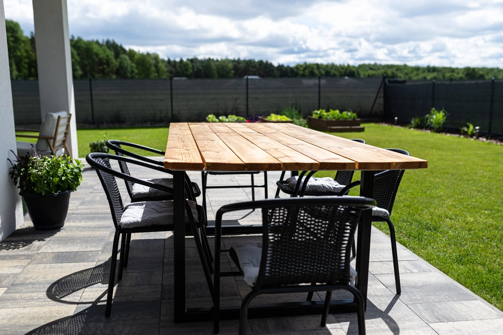Gepflasterte Terrasse mit Holztisch, Stühlen und Rasenfläche – Terrasse pflastern