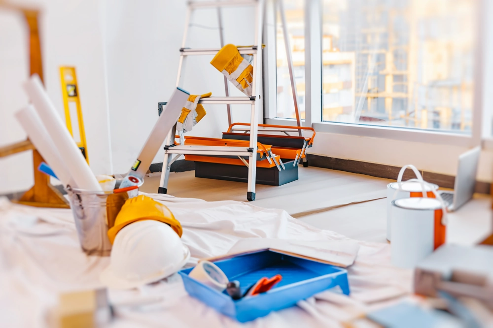 Arbeitsbereich für Malerarbeiten mit Leiter, Farbwanne, Schutzfolie und Werkzeug