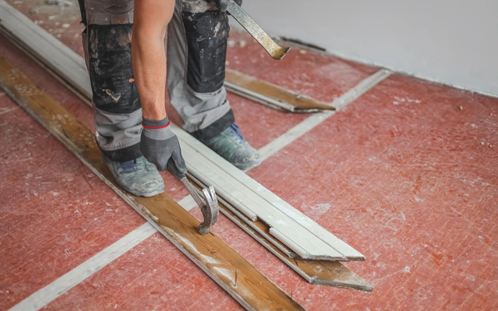 Handwerker demontiert mit Brechstange alte Holzdielen im Innenraum – Demontage