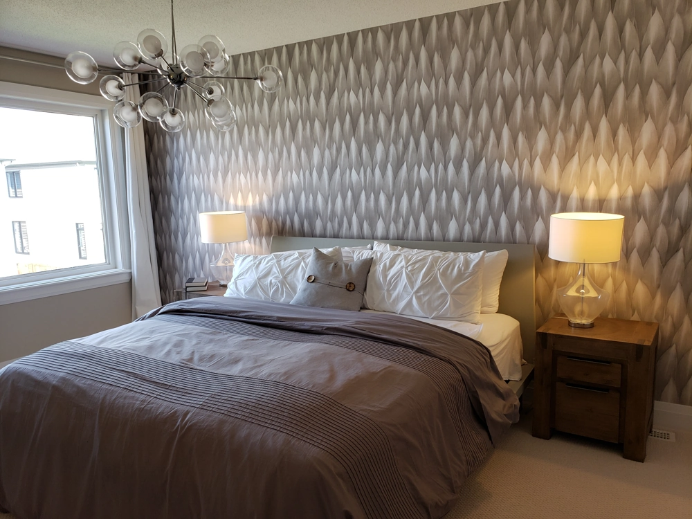 Schlafzimmer mit Tapezierarbeiten an gemusterten Wänden, Bett mit Holznachttischen und Lampen