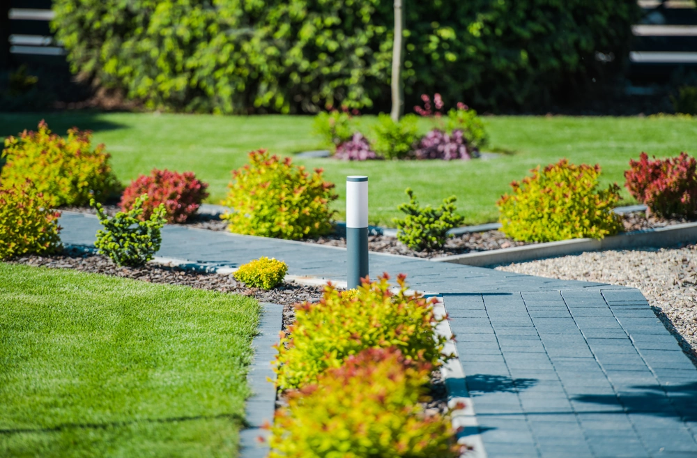 Gehwege pflastern: gepflasterter Gartenweg mit Rasen, Büscheinfassungen und Bodenleuchte
