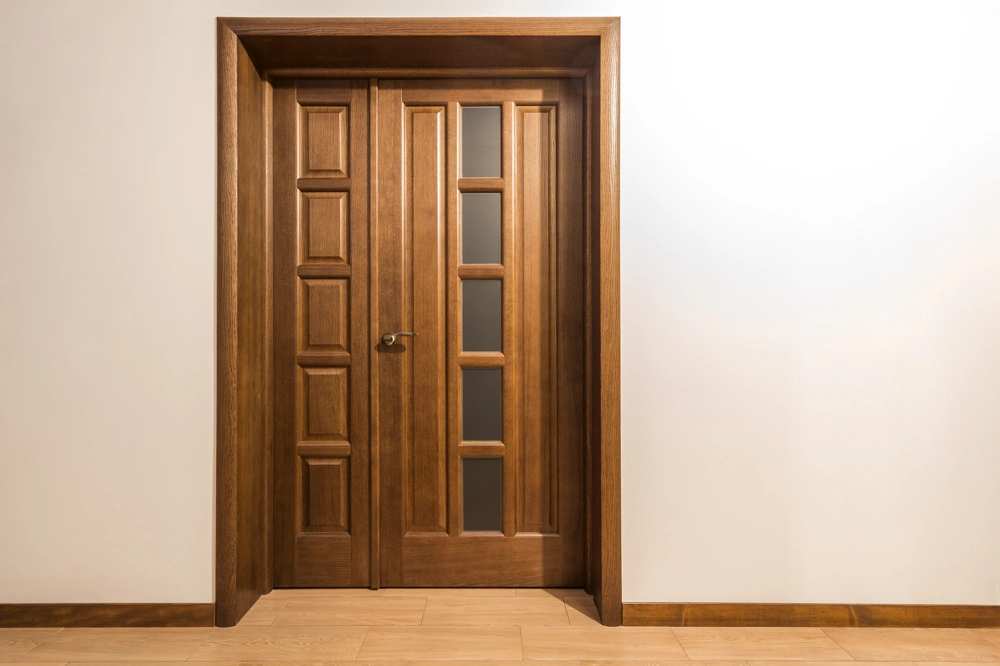 Zweiflügelige Holztür mit dekorativen Glaseinsätzen und Paneelverkleidung im Innenbereich – Türmontage