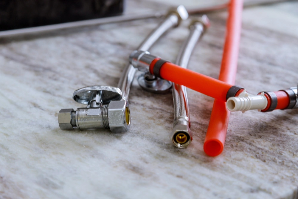 Metallabsperrventil, flexible Anschlussschläuche und PEX-Rohr für Sanitärinstallation auf Marmorarbeitsplatte