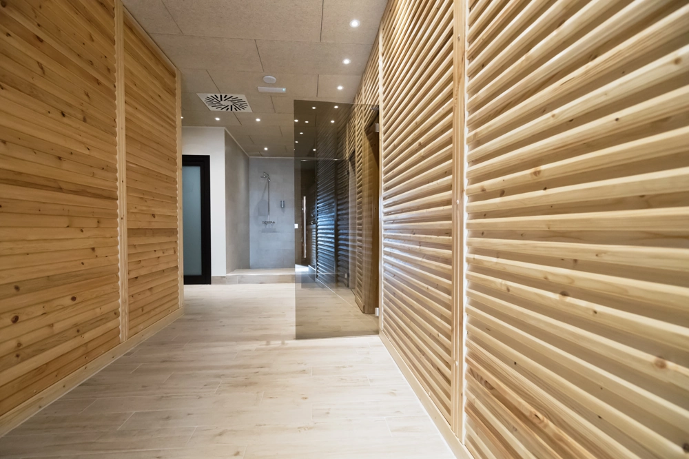 Moderner Flur mit Holzfußboden nach Bodenverlegung, Holzlamellenwand und integrierter Deckenspots